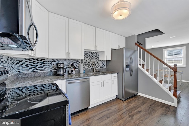 kitchen featuring dark stone countertops, a sink, stainless steel appliances, dark wood-type flooring, and white cabinetry