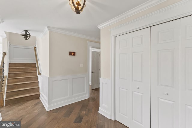 hall featuring dark wood-style floors, ornamental molding, stairway, and wainscoting