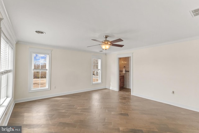 empty room with visible vents, crown molding, and wood finished floors