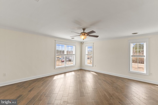 spare room featuring ornamental molding, dark wood-type flooring, plenty of natural light, and baseboards