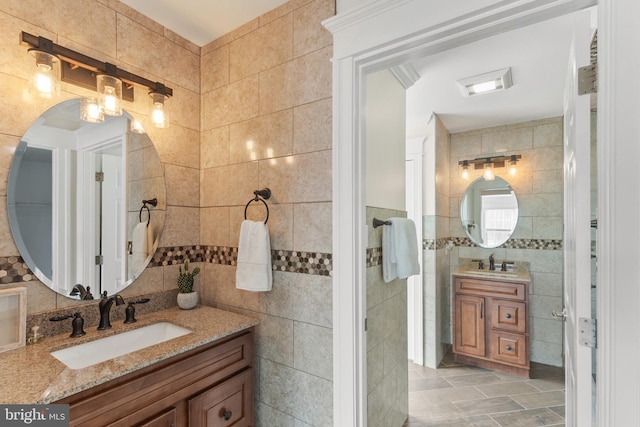 bathroom with tile walls, two vanities, and a sink