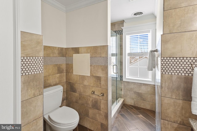 bathroom with toilet, visible vents, tile walls, ornamental molding, and a stall shower