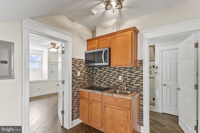 kitchen with electric panel, stainless steel microwave, dark wood-type flooring, black electric cooktop, and a sink