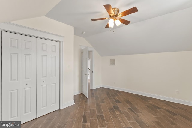 unfurnished bedroom with lofted ceiling, dark wood-type flooring, visible vents, baseboards, and a closet