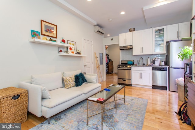 living room with recessed lighting, an AC wall unit, and light wood finished floors