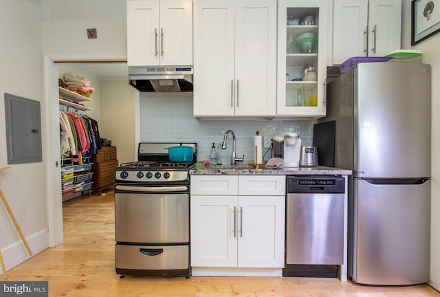 kitchen with under cabinet range hood, electric panel, appliances with stainless steel finishes, and white cabinets