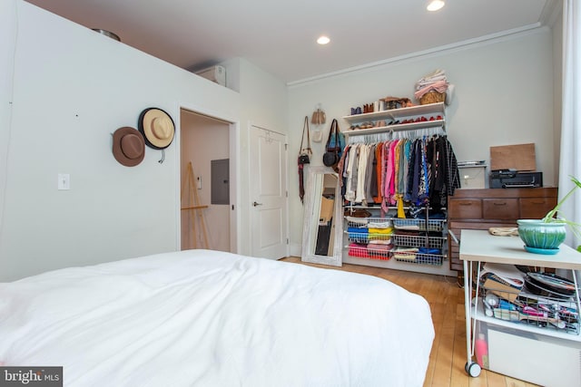 bedroom with light wood-style flooring, recessed lighting, a closet, electric panel, and crown molding