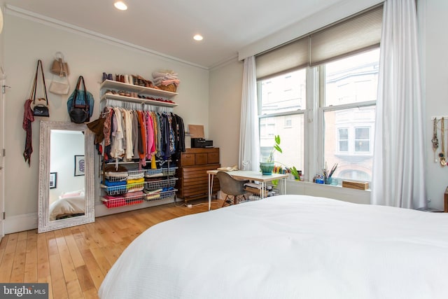 bedroom with a closet, recessed lighting, wood-type flooring, and crown molding