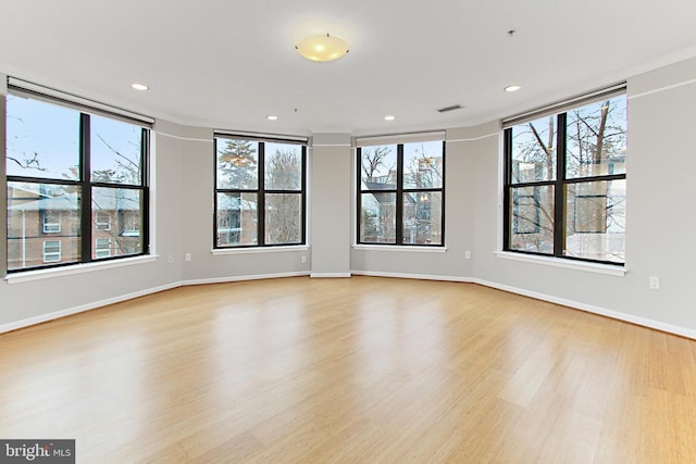 spare room with plenty of natural light, recessed lighting, baseboards, and light wood-style floors