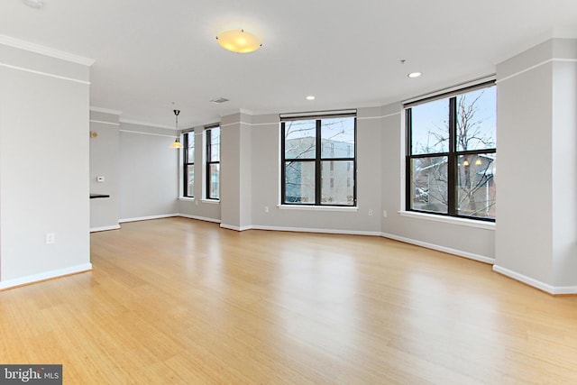 empty room featuring light wood finished floors, recessed lighting, baseboards, and ornamental molding