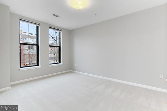 unfurnished room featuring baseboards, visible vents, and light carpet