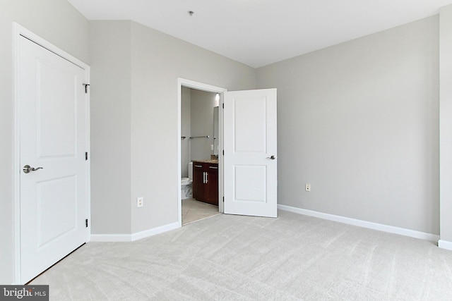 unfurnished bedroom featuring connected bathroom, baseboards, and light carpet