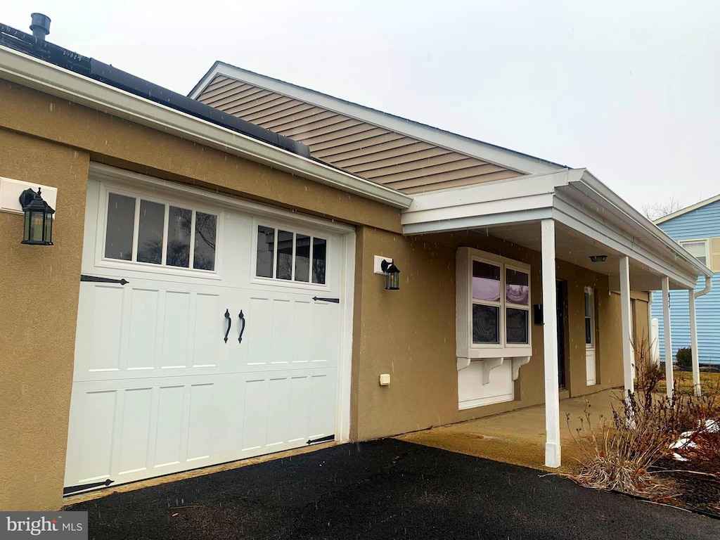 entrance to property featuring a garage and stucco siding