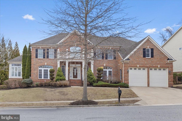 georgian-style home featuring concrete driveway, brick siding, and an attached garage