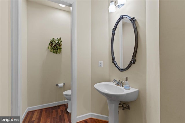 bathroom with toilet, baseboards, and wood finished floors