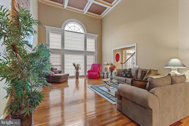 living area with hardwood / wood-style floors, beamed ceiling, coffered ceiling, and a towering ceiling