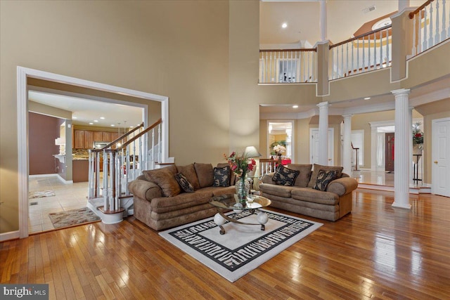 living room with light wood finished floors, decorative columns, stairs, and visible vents