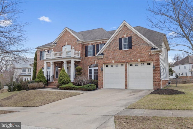 colonial inspired home with concrete driveway, brick siding, and a balcony