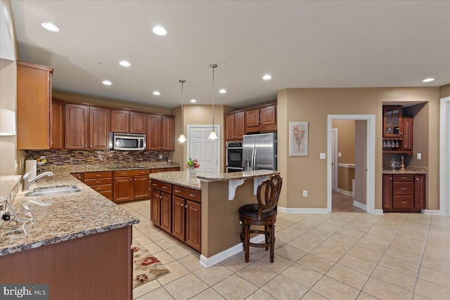 kitchen with light tile patterned floors, stainless steel appliances, tasteful backsplash, a sink, and a kitchen breakfast bar