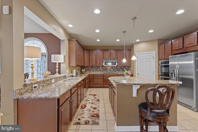 kitchen with a center island, a breakfast bar area, backsplash, appliances with stainless steel finishes, and a sink