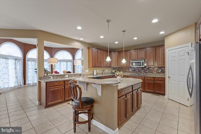 kitchen with appliances with stainless steel finishes, a kitchen breakfast bar, backsplash, and light tile patterned flooring