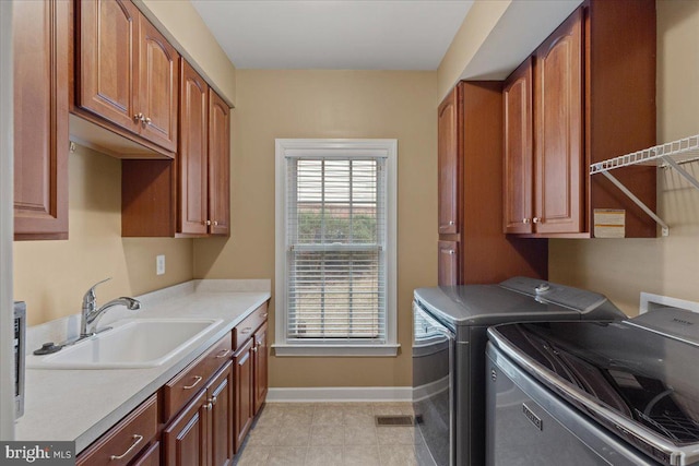 washroom featuring washing machine and dryer, a sink, cabinet space, and baseboards