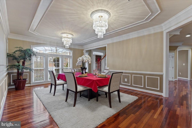 dining area featuring hardwood / wood-style flooring, ornamental molding, a decorative wall, and a notable chandelier