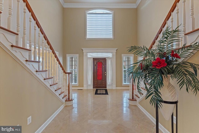 entrance foyer with a towering ceiling, marble finish floor, baseboards, and crown molding