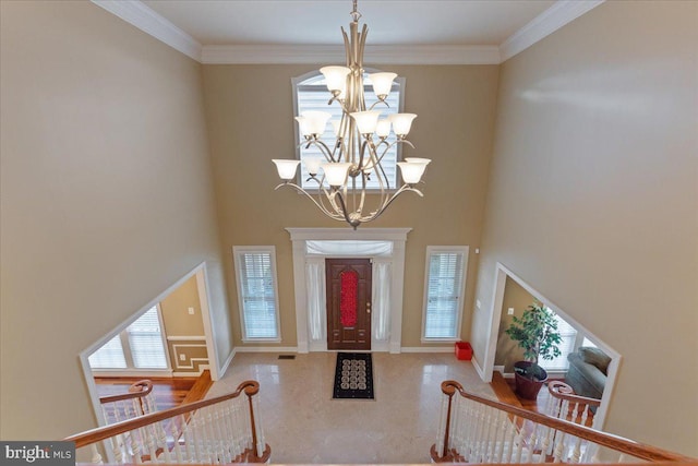 foyer entrance featuring ornamental molding, a towering ceiling, and a notable chandelier