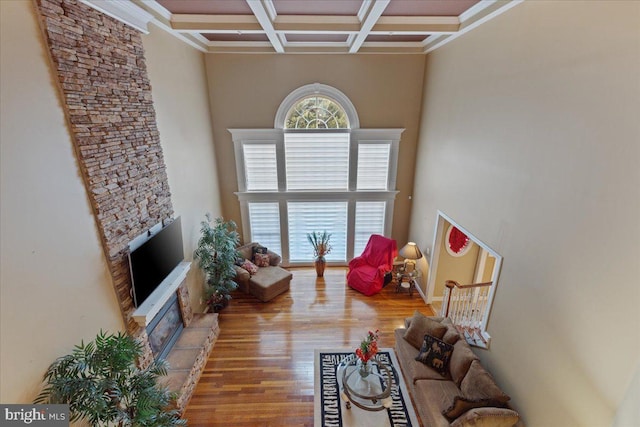 living area featuring beam ceiling, coffered ceiling, a high ceiling, and wood finished floors