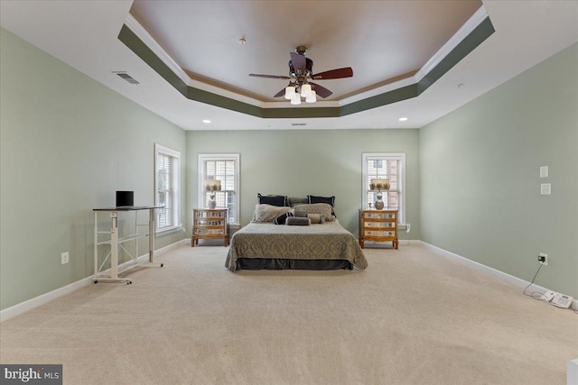 carpeted bedroom featuring ornamental molding, a raised ceiling, visible vents, and multiple windows