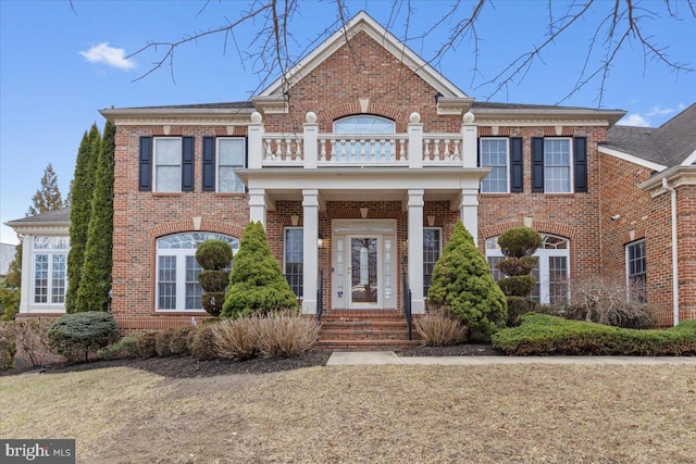 georgian-style home featuring a balcony and brick siding