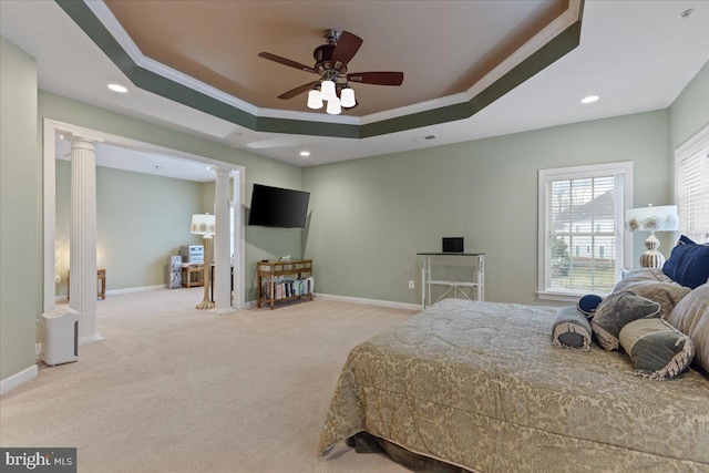 carpeted bedroom with baseboards, a tray ceiling, and ornate columns