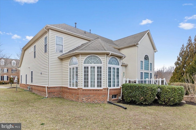 rear view of property featuring roof with shingles and a yard