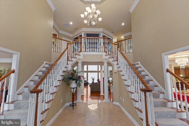 staircase featuring visible vents, baseboards, a towering ceiling, an inviting chandelier, and crown molding