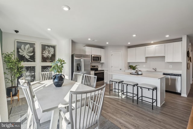 dining space featuring baseboards, wood finished floors, and recessed lighting