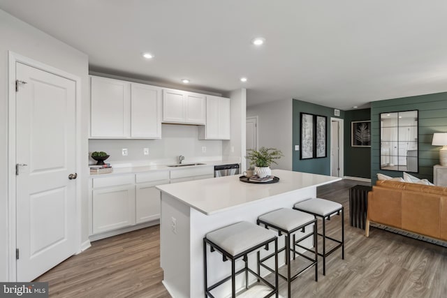 kitchen featuring dishwasher, light wood-type flooring, a sink, and a center island