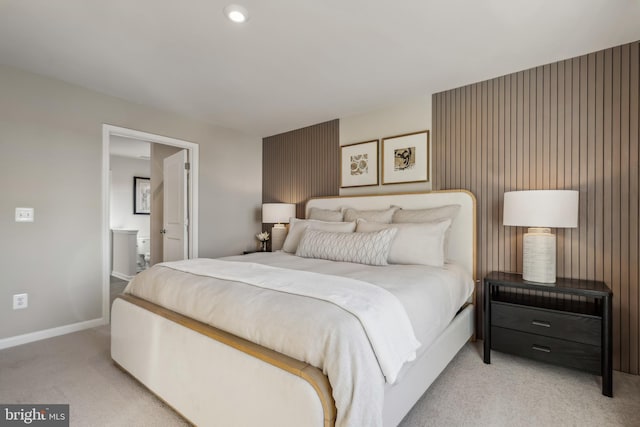 bedroom with light carpet, ensuite bath, and baseboards