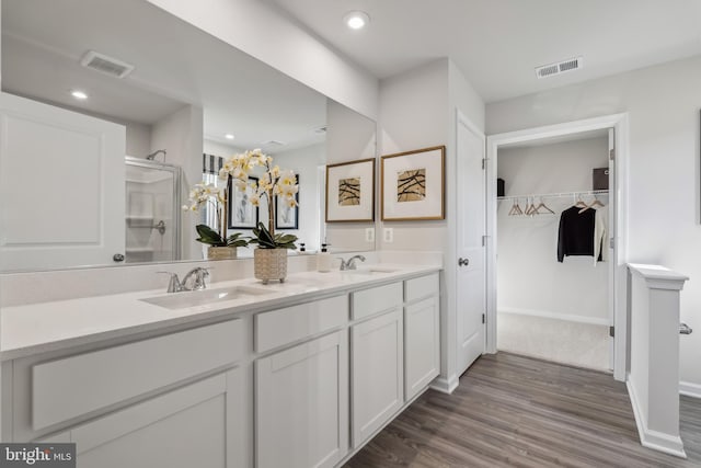 bathroom featuring a shower with door, visible vents, and a sink