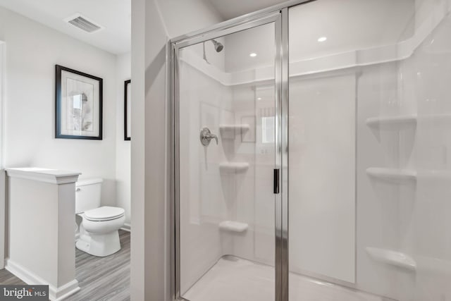 bathroom featuring a stall shower, visible vents, toilet, and wood finished floors