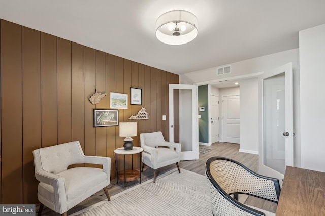 living area with french doors, visible vents, baseboards, and wood finished floors