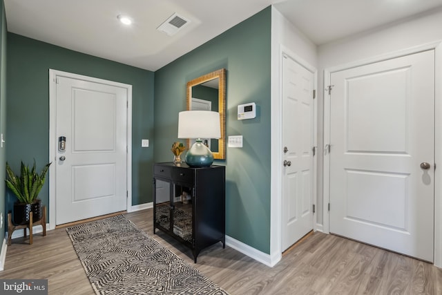 foyer with baseboards, visible vents, and light wood finished floors