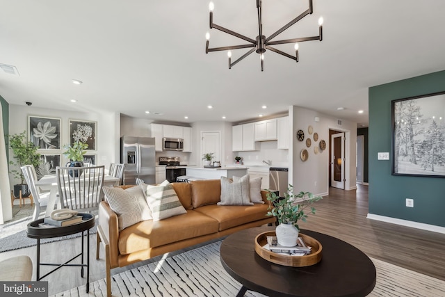 living room with visible vents, baseboards, wood finished floors, an inviting chandelier, and recessed lighting