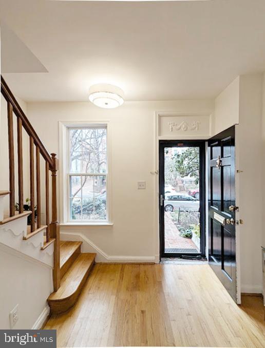 entrance foyer with stairs, wood finished floors, and baseboards