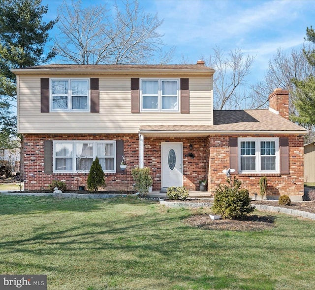 view of front facade featuring a front yard, brick siding, a chimney, and a shingled roof