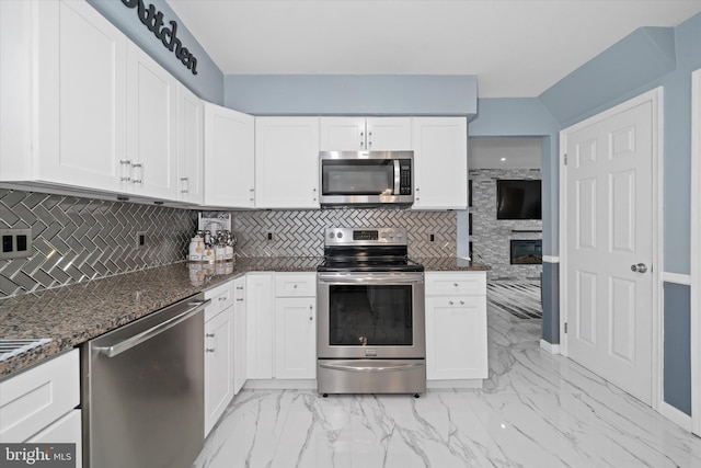 kitchen with dark stone countertops, marble finish floor, and appliances with stainless steel finishes