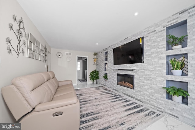 living room with recessed lighting, visible vents, marble finish floor, and a glass covered fireplace