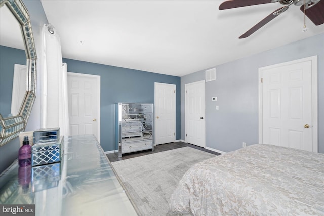 bedroom with a ceiling fan, wood finished floors, baseboards, visible vents, and a closet