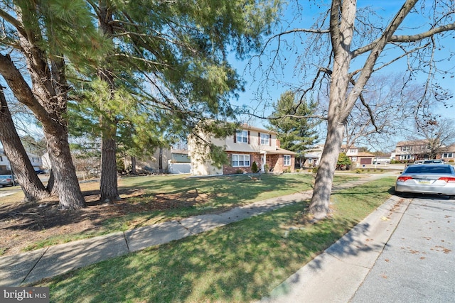 view of front of house with a front lawn, brick siding, and a residential view