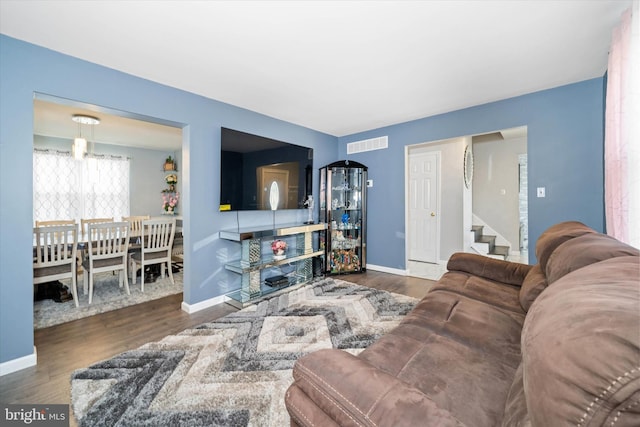 living room with stairs, wood finished floors, visible vents, and baseboards